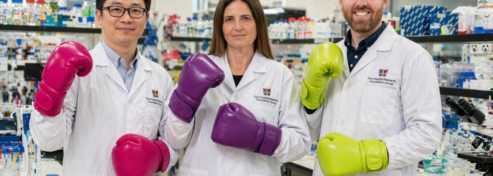 3 researchers in a lab wearing boxing gloves