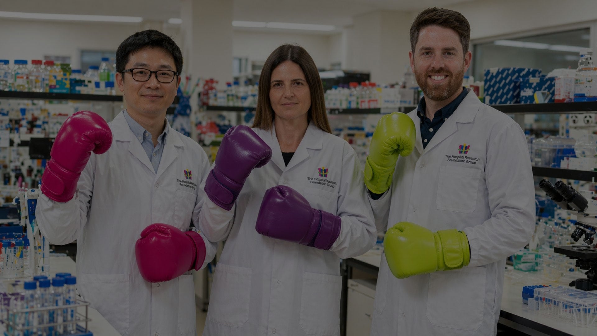 3 researchers in the lab wearing boxing glove overlay